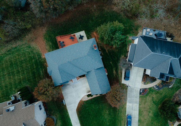 A gray hip-and-valley shingle roof seen straight down beside its neighbor